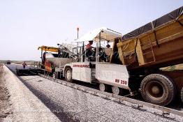 Image du Maroc Professionnelle de  Travaux sur la voie en construction Sidi el Yamani-Asilah installation de la première épaisseur de la couche de revêtement de la chaussée, Mercredi 12 Juin 2002. (Photo / Abdeljalil Bounhar) 